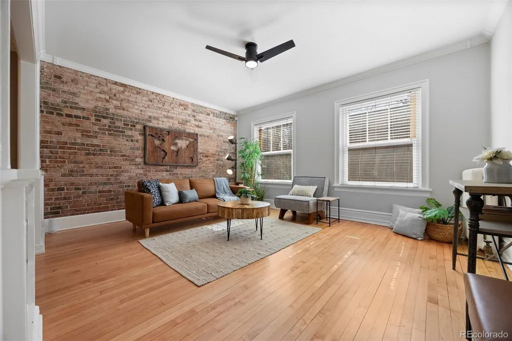 Living room seen from the corner, with the brick wall, ceiling fan and windows