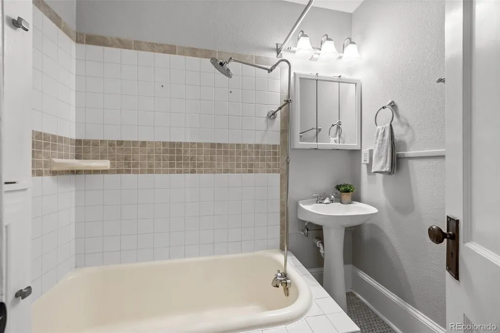 Bathroom with a tub, tiled walls and a pedestal sink